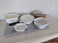 Entire lot: four square casseroles, two glass lids, oval glass casserole with lid, detachable handle