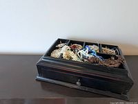 Jewelry box with top tray holding assorted necklaces and earrings