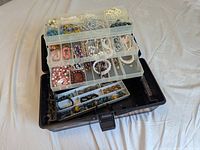 overview of open black plastic toolbox showing tiered trays filled with assorted jewelry pieces