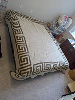 Blanket on bed showing cream side with Greek key border