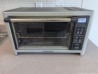Front view of Hamilton Beach toaster oven showing stainless housing, glass door and overall wear
