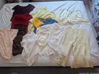 All 11 knit and crochet garments laid out on bed