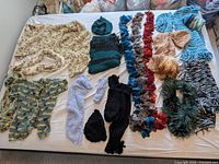 Overall view of all knitted scarves, hats and headband spread on bed