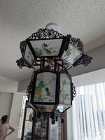 Overall view of wooden chandelier with painted glass panels hanging from ceiling