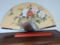 Full view of folding fan displayed on furniture with storage sleeve below