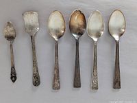 Front view showing all six pieces in order: small spoon, scoop, four matching teaspoons