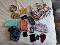 All 15 coin purses, pouches and tote laid out on bed
