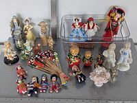 Overall group of porcelain figures, cloth dolls, nesting dolls, fans, accessories with ruler for scale
