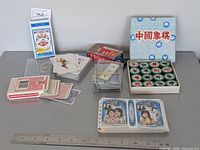 Overall lot showing all playing card decks, Xiangqi pieces, pop idol album, ruler for scale