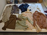 Eight assorted cardigans laid out on bed