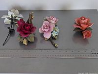 Four porcelain flower figurines with ruler for scale