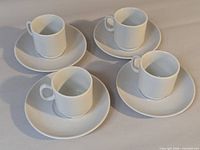 Four demitasse cup-and-saucer sets displayed