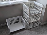 Four white plastic baskets, three stacked, one separate