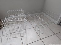 all six white wire baskets on floor, showing sizes and hook design