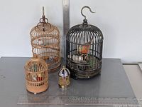 All four bird cages grouped to show size range and materials