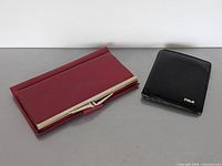 Red Tilley clutch wallet and black Polo bi-fold wallet closed, showing exterior condition