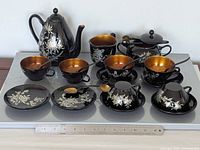 Entire 15-piece lacquer tea/coffee set laid out with ruler for scale