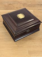 Closed box angled view showing wood finish, lid plaque, lock