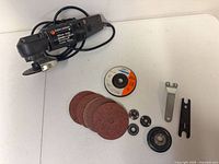Angle grinder with cord, sanding discs, wheels, wrenches, spindle hardware laid out