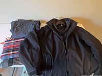 Weatherproof jacket on hanger with folded rain pants visible