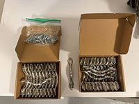Two open boxes showing stacked metal cabinet pulls, bag of screws visible