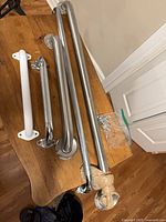 Five grab bars laid out on table, mixed finishes and lengths