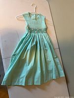 Front view of mint green sleeveless smocked dress on hanger