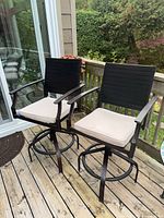 Front view of two metal swivel chairs with beige cushions on deck