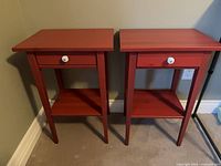 Front view of both red wood side tables showing drawers, shelves and finish
