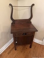 Front view of dark brown solid wood washstand with towel bar, drawer closed, cabinet door closed