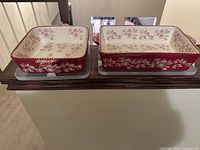 Top view of square and rectangular dishes showing red exterior and ivory interior floral pattern