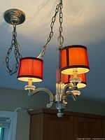 Close view of chandelier showing shades, arms, glass column and chains