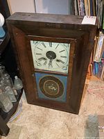 Front view of wood OGEE clock showing dial and reverse-painted lower glass