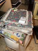 Stack of two floral fabric binders with lace edges, filled with linens