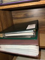 stacked burgundy binder and green binder on shelf
