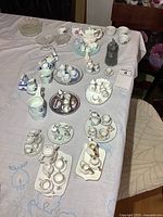 Table overview showing multiple miniature tea sets, glass dishes, stacking cups, figurine