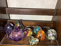 Eight assorted glass paperweights on shelf