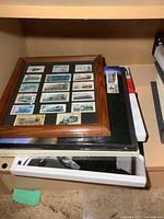 Shelf with framed stamp display, two binders, additional tray