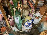 Group shot of assorted teapots on bottom glass shelf