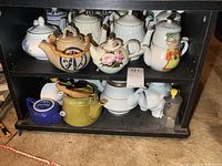 Full view of two-shelf unit showing majority of teapots and moka pot