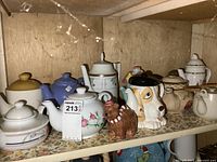 Shelf showing group of assorted teapots and bear figurine