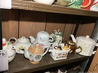 Shelf showing seven assorted teapots side by side