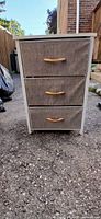 Front view showing three grey fabric drawers with wooden handles