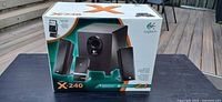 Front of retail box showing subwoofer, satellites, control pod, model X-240