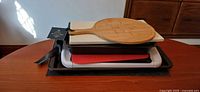 Stacked view showing bamboo cheese board, assorted cutting boards, baking pans