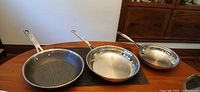 Three stainless steel pans side by side on table