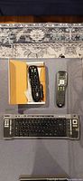 Lot overview showing Logitech remote in box, Microsoft keyboard, HP remote