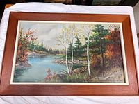 Full view of framed autumn riverscape painting