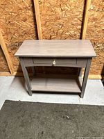 full view of console table showing drawer, glass knob, lower shelf, gray finish