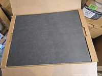 Stack of black Bristol board sheets in shipping carton